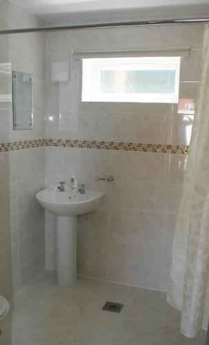 baño blanco con lavabo y ventana en Castle Lodge, en Crosskeys