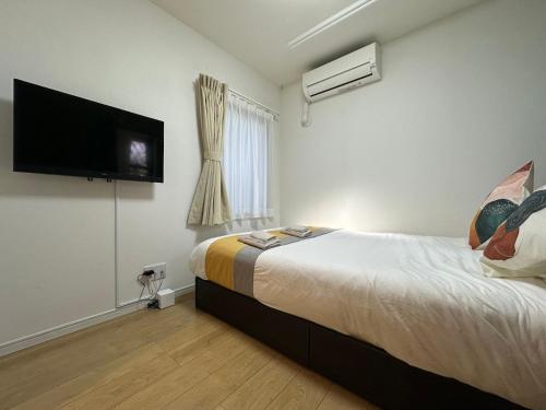 a bedroom with a bed and a flat screen tv at nestay inn tokyo kagurazaka in Tokyo