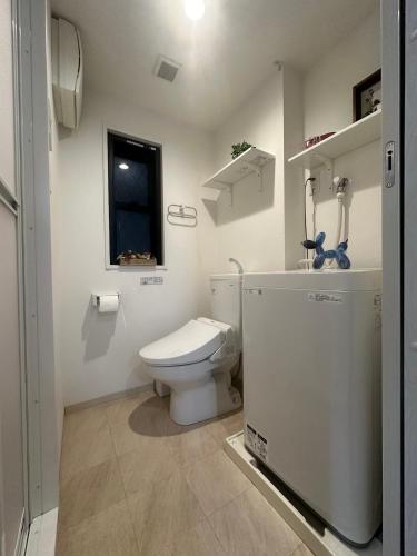 a white bathroom with a toilet and a window at nestay inn tokyo kagurazaka in Tokyo