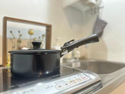 a pot on top of a stove with a remote control at nestay inn tokyo kagurazaka in Tokyo