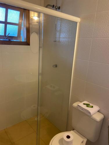 a bathroom with a toilet and a glass shower at Hospedaria Morada das Orquídeas in São Sebastião