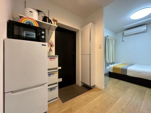 a room with a refrigerator with a microwave and a bed at nestay inn tokyo kagurazaka in Tokyo
