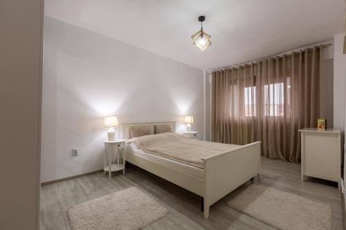 una camera bianca con un letto e una finestra di Apartament Alexandru - central a Mediaş