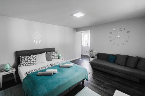 1 dormitorio con cama, sofá y reloj en Sunny Garden Apartment, en Bogács