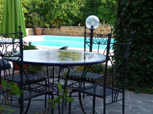 a patio table and chairs with a pool in the background at Poggio Delle Palme in Campobello di Licata