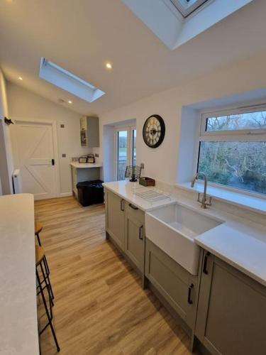 uma cozinha com um lavatório e um relógio na parede em Riverbank Cottage, Dog Friendly. Swansea, Llanelli em Hendy