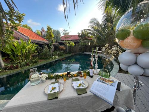 a table with plates of food next to a swimming pool at Pao Homes - An Bang Beach Stone Villa in An Bang