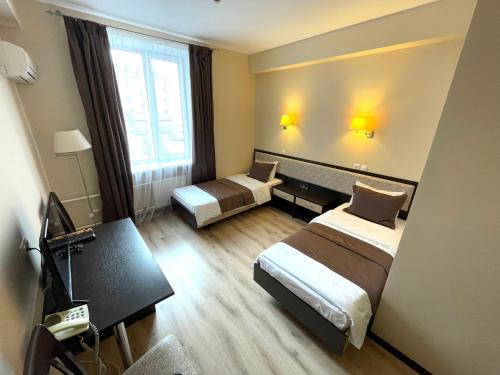 Pokój hotelowy z 2 łóżkami i biurkiem w obiekcie Hotel Korona w mieście Magnitogorsk