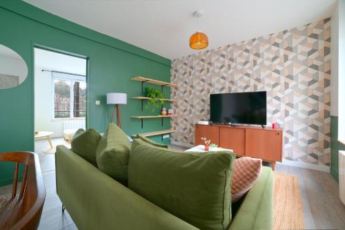 a living room with a green couch and a tv at Le Relais Poitevin - Grand T3 proche gare in Poitiers