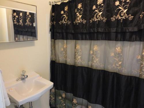 a bathroom with a sink and a black shower curtain at Theater Motel in Westfield
