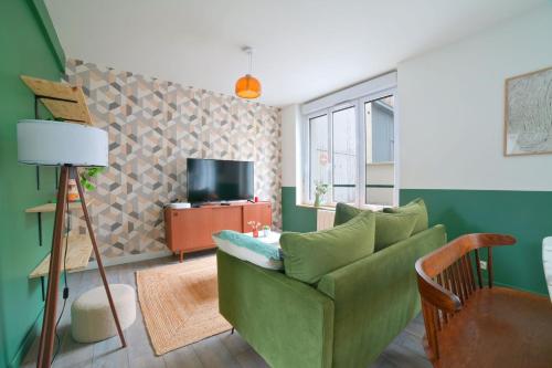 a living room with a green couch and a television at Le Relais Poitevin - Grand T3 proche gare in Poitiers