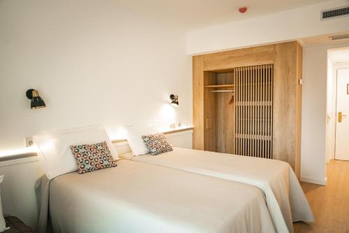 una camera da letto con un letto bianco con due cuscini sopra di htop Amatista #htopBliss a Lloret de Mar