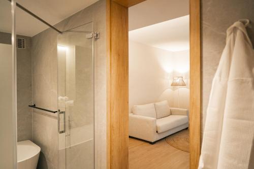 a bathroom with a shower and a white chair at htop Amatista #htopBliss in Lloret de Mar
