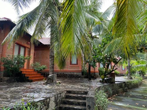 a house with palm trees in front of it at Birdofparadisehomestay in Ấp Phú Sum