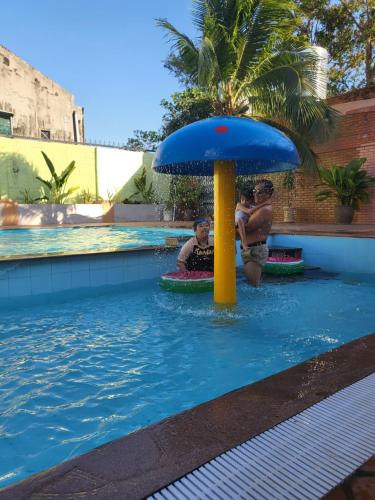 two people sitting under a blue umbrella in a swimming pool at Birdofparadisehomestay in Ấp Phú Sum