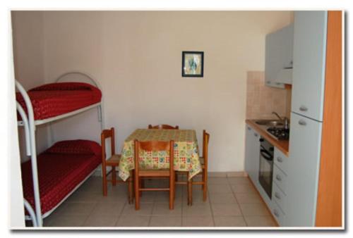 a small kitchen with a table and a room with bunk beds at Appartamenti Villa Miramare in Capoliveri