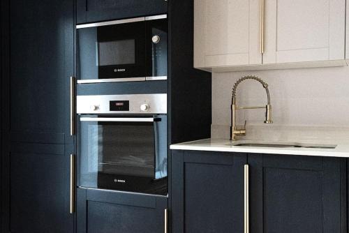 a kitchen with a microwave oven and a sink at Home at Highgrove - Private Garden & Parking in Reading