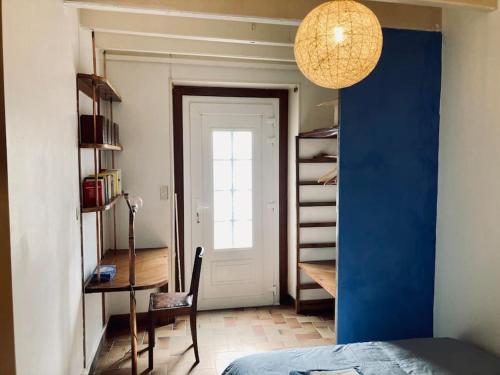 1 dormitorio con pared azul, escritorio y puerta en Maison de campagne - La Belle Claudine, en Laruscade