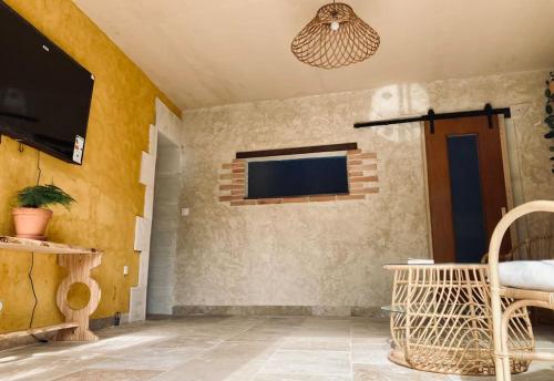 un salon avec une télévision sur un mur dans l'établissement Maison de campagne - La Belle Claudine, à Laruscade