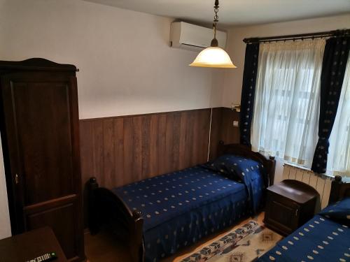 a bedroom with a blue bed and a window at Hotel Bolyarka in Melnik