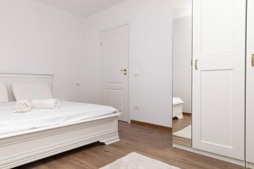 a white bedroom with a bed and a mirror at Enescu 3 City Center Flat in Timişoara
