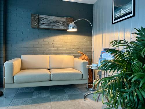 a white couch in a room with a brick wall at Modern Seaside Townhouse feat Sauna near Brighton in Shoreham-by-Sea