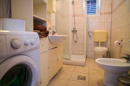 a bathroom with a washing machine and a sink at Apartmani Helena in Mali Lošinj