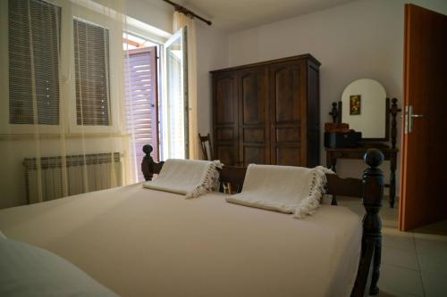 a bedroom with a bed with white sheets and a window at Apartmani Helena in Mali Lošinj