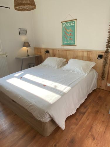 een slaapkamer met een groot bed met witte lakens bij Hôtel L'Arbousier in Soulac-sur-Mer