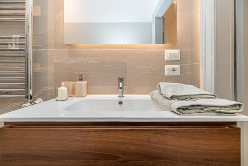 La salle de bains est pourvue d'un lavabo blanc et d'un miroir. dans l'établissement Art Around In Monti House, à Milan