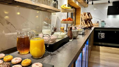 una encimera con vasos de zumo de naranja y rosquillas en Alpen Lodge Riezlern, en Riezlern