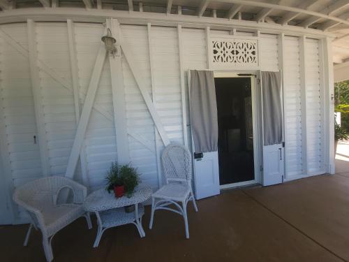 a porch with two chairs and a table and a door at Ribbonwood Bed & Breakfast, Emu Park Qld in Emu Park