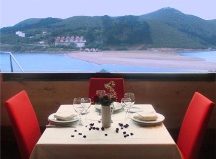 a table with red chairs and a table with wine glasses at Bungalows Portuondo parking gratuito in Mundaka
