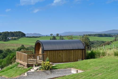 um edifício de madeira no meio de um campo em Luxury Glamping Pods - The Heft & The Hirsel em Glasgow