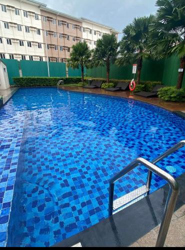 a large swimming pool with blue tiles in front of a building at Condotel Minimalist in Marilao