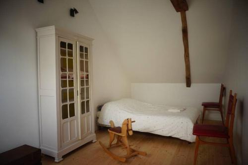 a bedroom with a white bed and a wooden chair at belle maison de campagne in Hénon