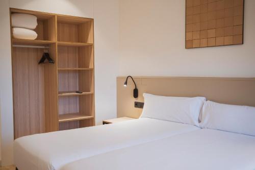 a bedroom with a white bed and a book shelf at Hotel Sant Pau in Barcelona