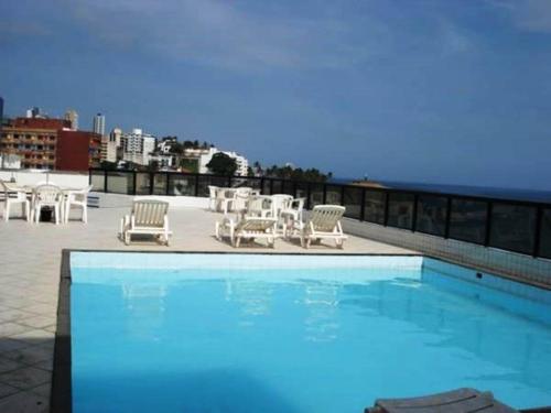 a swimming pool with chairs and tables on a roof at Flat no Farol da Barra in Salvador