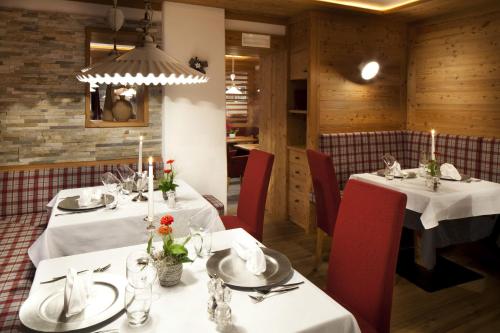 a dining room with two tables and red chairs at Hotel Christian in Corvara in Badia