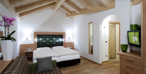 a bedroom with a bed and a tv and a couch at Hotel Christian in Corvara in Badia