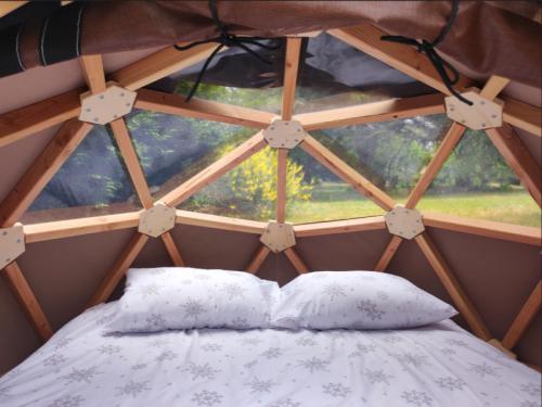 ein Bett mit zwei Kissen in einem Zimmer mit einem Fenster in der Unterkunft Camping Nature et insolite proche Disneyland in Saâcy-sur-Marne