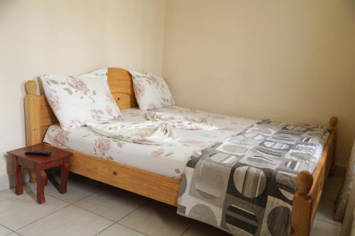 a small bed with a wooden frame and a table at Kigali guesthouse: shared property with individual rooms in Kigali