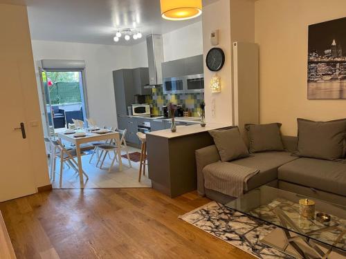 a living room and kitchen with a couch and a table at T2 jacuzzi à 15mn stade de France porte de paris in Épinay-sur-Seine