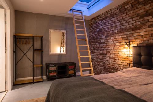 a room with a bed and a ladder on a brick wall at Drive-in appartement centrum Alkmaar in Alkmaar