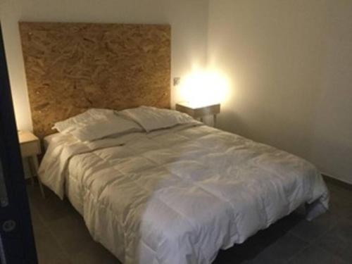 ein Schlafzimmer mit einem großen weißen Bett und einer Lampe in der Unterkunft Maison rénovée au calme in Gujan-Mestras