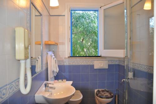 baño de azulejos azules con lavabo y ventana en Marettimo Residence, en Marettimo