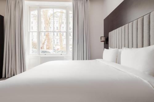 a bedroom with a large white bed and a window at Rove Hotel London Paddington in London