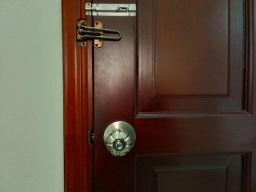 a wooden door with a metal knocker on it at Hostel Đặng Lợi ホステルダンロイ in Chau Doc