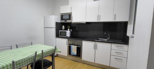 a kitchen with white cabinets and a table and a microwave at Residencial Monaco in Funchal