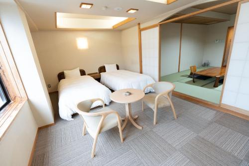 a room with two beds and a table and chairs at Arimakan in Kaminoyama